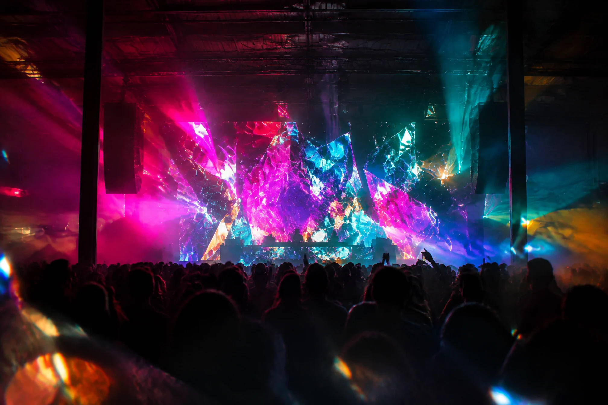 Festival stage with a wall of shattered neon pixel shapes above a crowd