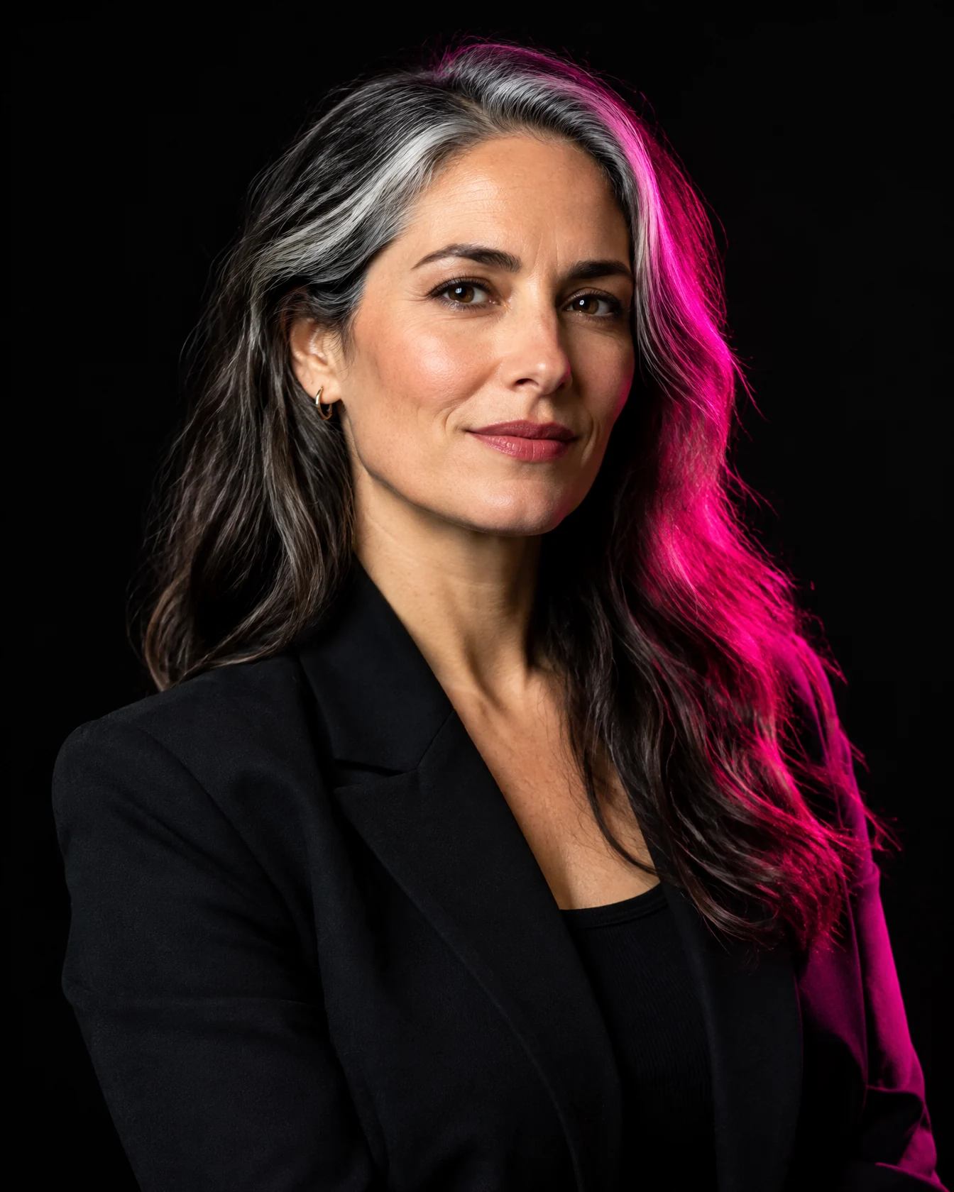 Creative director with silver-streaked hair in a black blazer, pink rim light
