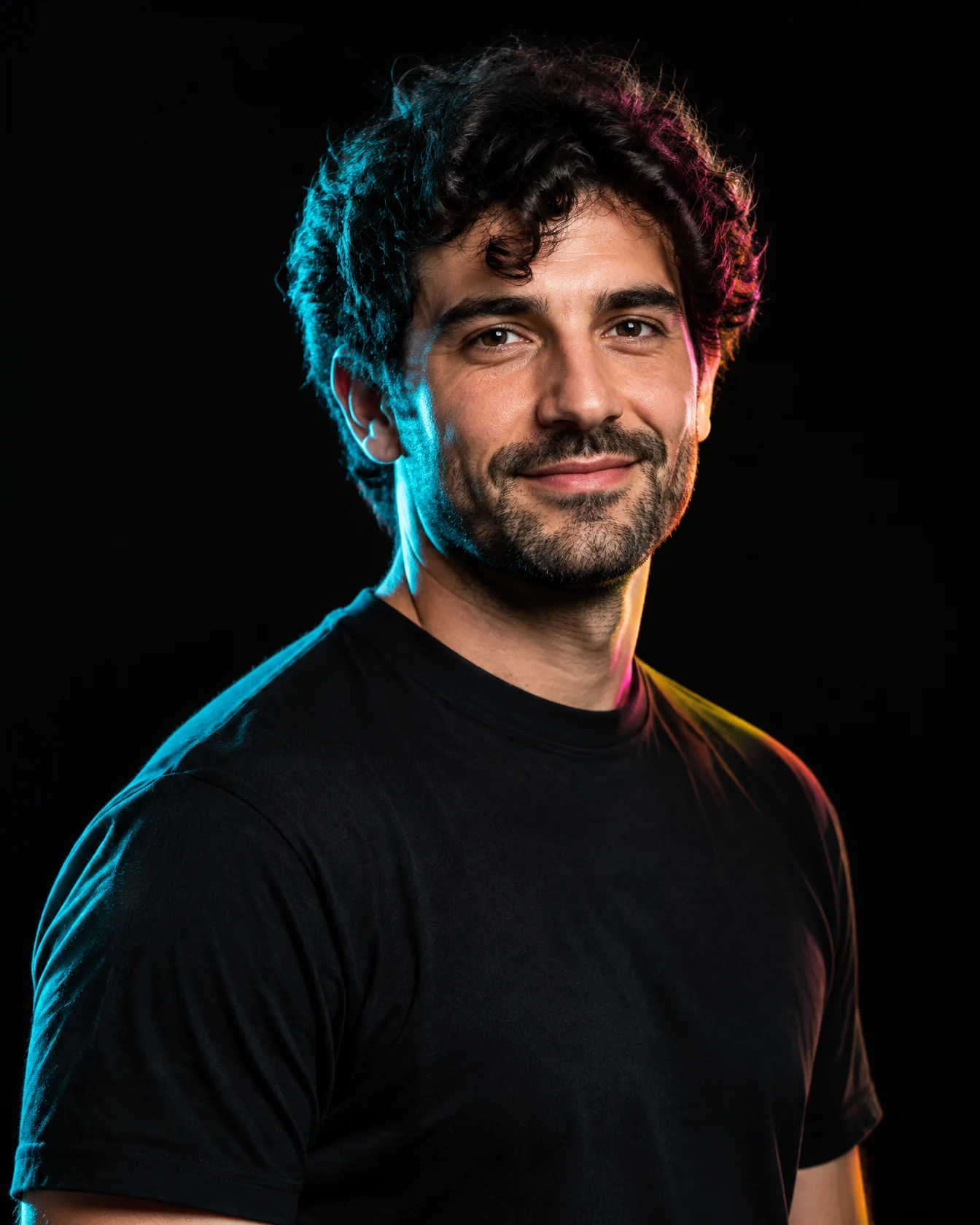 Art director with dark curly hair in a black tee, teal rim light